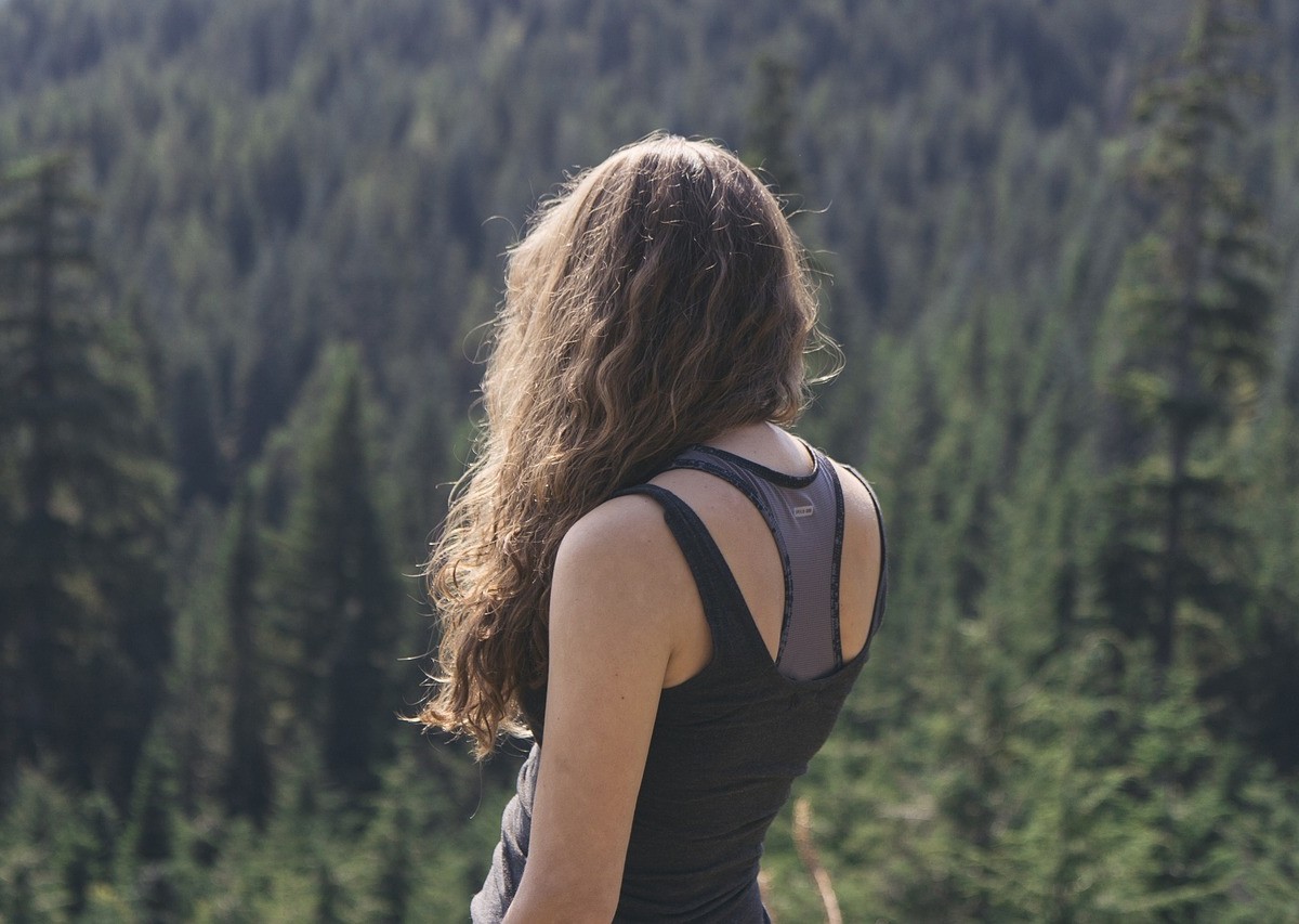 女性が目の前に広がる森を見ている写真